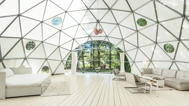 A spacious room with a geometric ceiling, a bed, a sofa, and a small table. - Outlier Inn Large Dome on Farm Upstate Catskills (Woodridge)