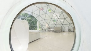 A circular viewing area with a geometric ceiling design, a wooden floor, and a white wall. - Outlier Inn Large Dome on Farm Upstate Catskills (Woodridge)