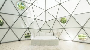 A bedroom with a geometric ceiling, a bed, and circular windows. - Outlier Inn Large Dome on Farm Upstate Catskills (Woodridge)