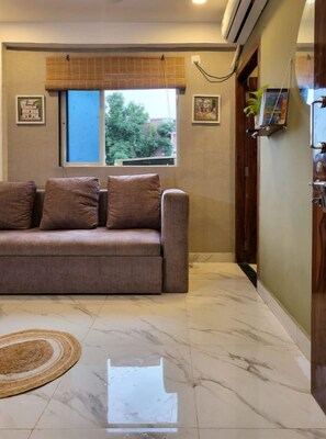 A living room with a sofa, a window, and a door.