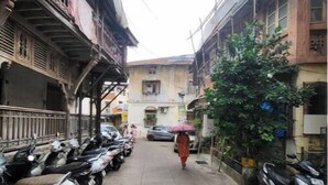 Una calle estrecha bordeada de scooters estacionados y un peatón alejándose de la cámara.