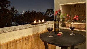 A balcony with a table, two wine glasses, a bottle, and candles. - Studio c/ churrasq 650m da Torre Panorâmica RME047 (Curitiba)