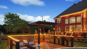 A backyard with a swimming pool, wooden deck, and outdoor seating area.