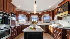 A spacious kitchen with wooden cabinets, a central island, and a large window providing natural light.