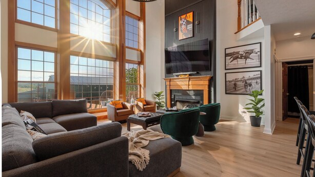A spacious living room with a large sectional sofa, a fireplace, and a view of the outdoors through large windows.