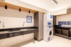 A modern bathroom with a black countertop, a washing machine, and a sink. - Beautiful and Functional Apartments in Curitiba - WSH (Curitiba)