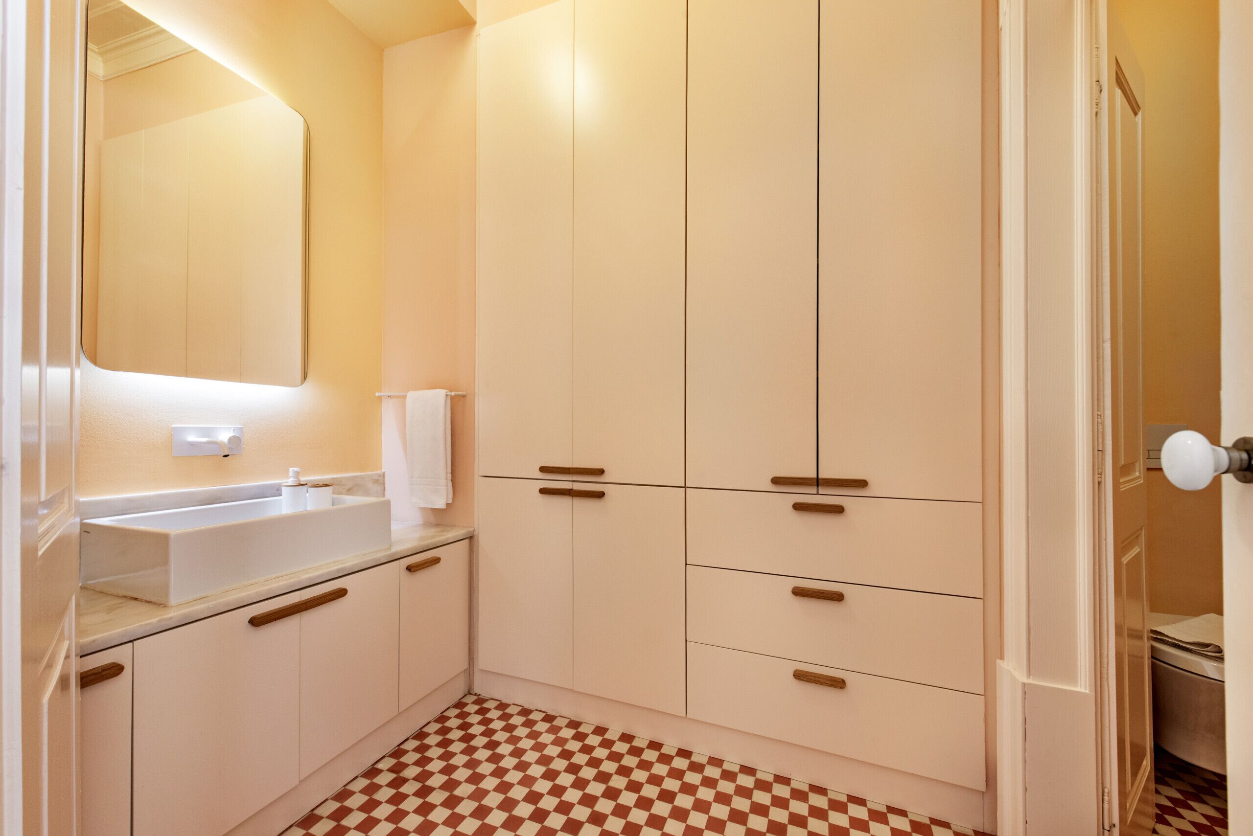 A bathroom with a checkered floor, a sink, and cabinets.