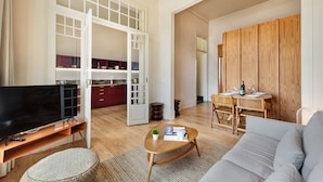 A spacious living room with a flat-screen TV, a sofa, a coffee table, and a dining area with a wooden table and chairs. - PG - 1D - T2 Superior - Palacete do Guadiana (Vila Real Santo Antonio)