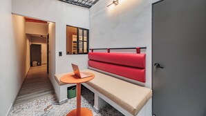 Una habitación moderna con un banco, una mesita, una computadora portátil y una puerta.