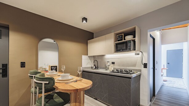 Una cocina moderna con una isla central, un comedor con mesa redonda y sillas, y un espejo grande.
