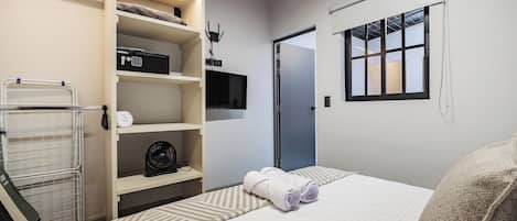 A bedroom with a bed, a wardrobe, a TV, and a window.