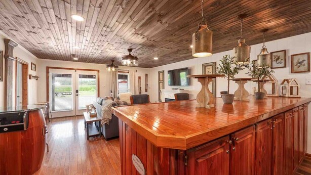 A spacious kitchen with a wooden island, pendant lights, and a view to the outdoors.