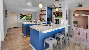 Eine moderne Küche mit blauen Schränken, einer zentralen Kochinsel und einer Bar mit Barhocker.