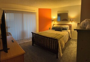 Une chambre à coucher avec un lit, des tables de chevet, un miroir et une fenêtre avec des stores.