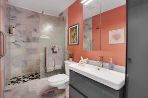 Une salle de bain avec douche, toilettes et lavabo.