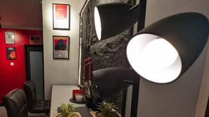 A modern dining area with a stone accent wall, a clock, and a table with chairs. - Escape Studio (Kingston)