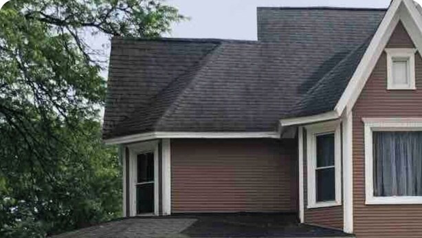 Ein zweigeschossiges Haus mit Veranda, Garage und Schornstein.