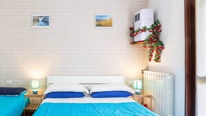 Ein Hotelzimmer mit einem Bett, zwei Nachttischen mit Lampen, einem Heizkörper und zwei gerahmten Bildern an der Wand.