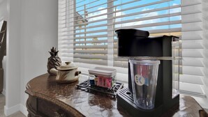 A kitchen counter with a coffee maker, a kettle, and a glass container.