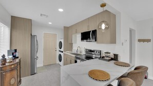 A modern kitchen with a central island, built-in appliances, and a pendant light.