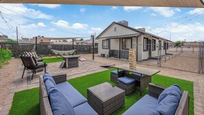 A patio with outdoor furniture, a small house, and a fenced area.