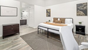 Een moderne slaapkamer met een bed, een dressoir, een kaptafel en een plafondventilator.