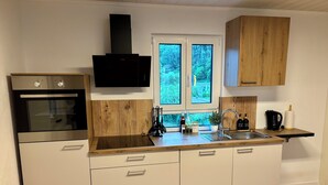 Une cuisine moderne équipée d’un four encastré, d’une cuisinière, d’un évier et de meubles de rangement en bois.