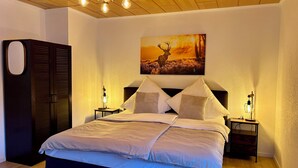 Une chambre à coucher avec un grand lit, deux tables de chevet avec des lampes, une armoire et un tableau au mur.