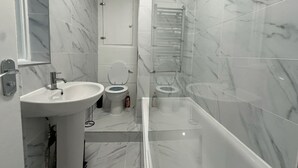 Ein modernes Badezimmer mit Waschbecken, zwei Toiletten und einer Duschkabine.