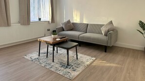 Ein modernes Wohnzimmer mit einer Couch, einem Couchtisch und einem Fenster mit Vorhängen.