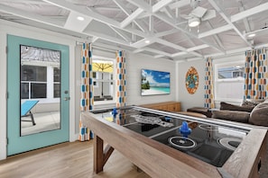 A room with a pool table, a door leading to an outdoor area, and a view of the outdoors.