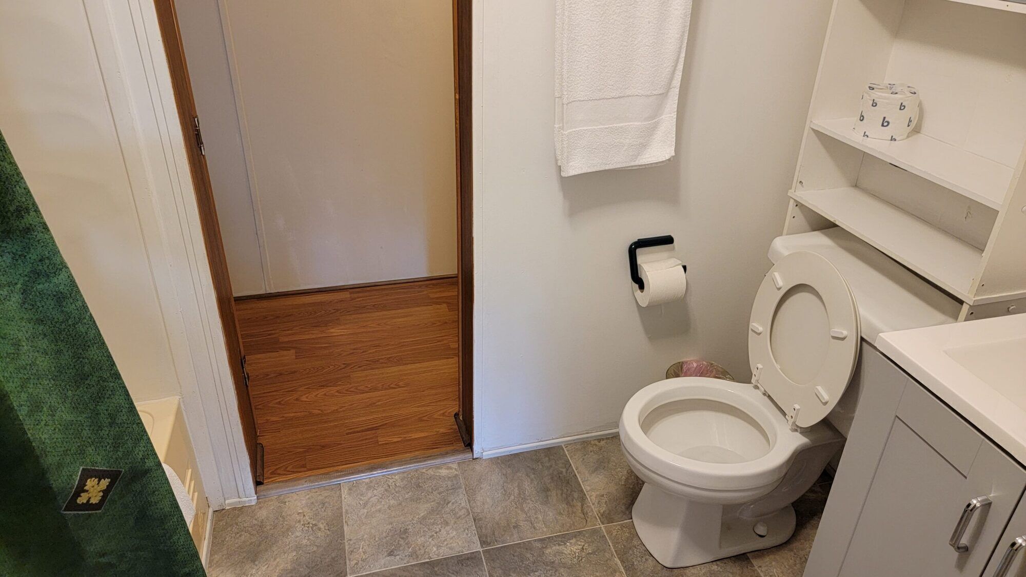 Une salle de bain équipée de toilettes, d’un porte-serviettes et d’un support à papier toilette.