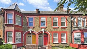A row of terraced houses with red brick facades and white window frames. - Newly refurbished 2 bedroom apartment in trendy Leyton (London)
