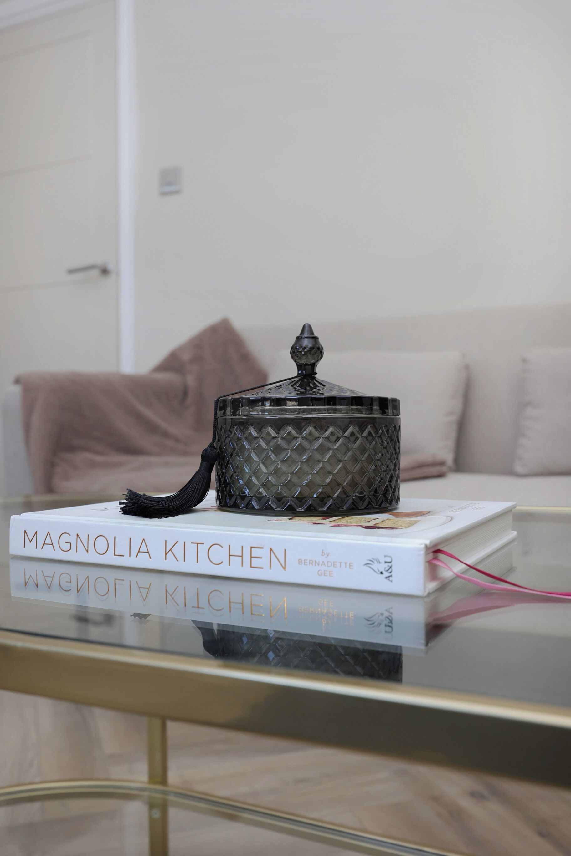 A kitchenware item on a glass table with a book titled "Magnolia Kitchen" by Bernadette Glee.