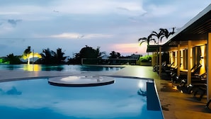 A swimming pool with a circular feature, surrounded by lounge chairs and a building with outdoor seating. - SONESTA (Cartagena)