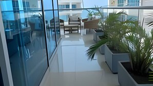 A modern apartment with a glass wall, a balcony with potted plants, and a view of other buildings. - SONESTA (Cartagena)