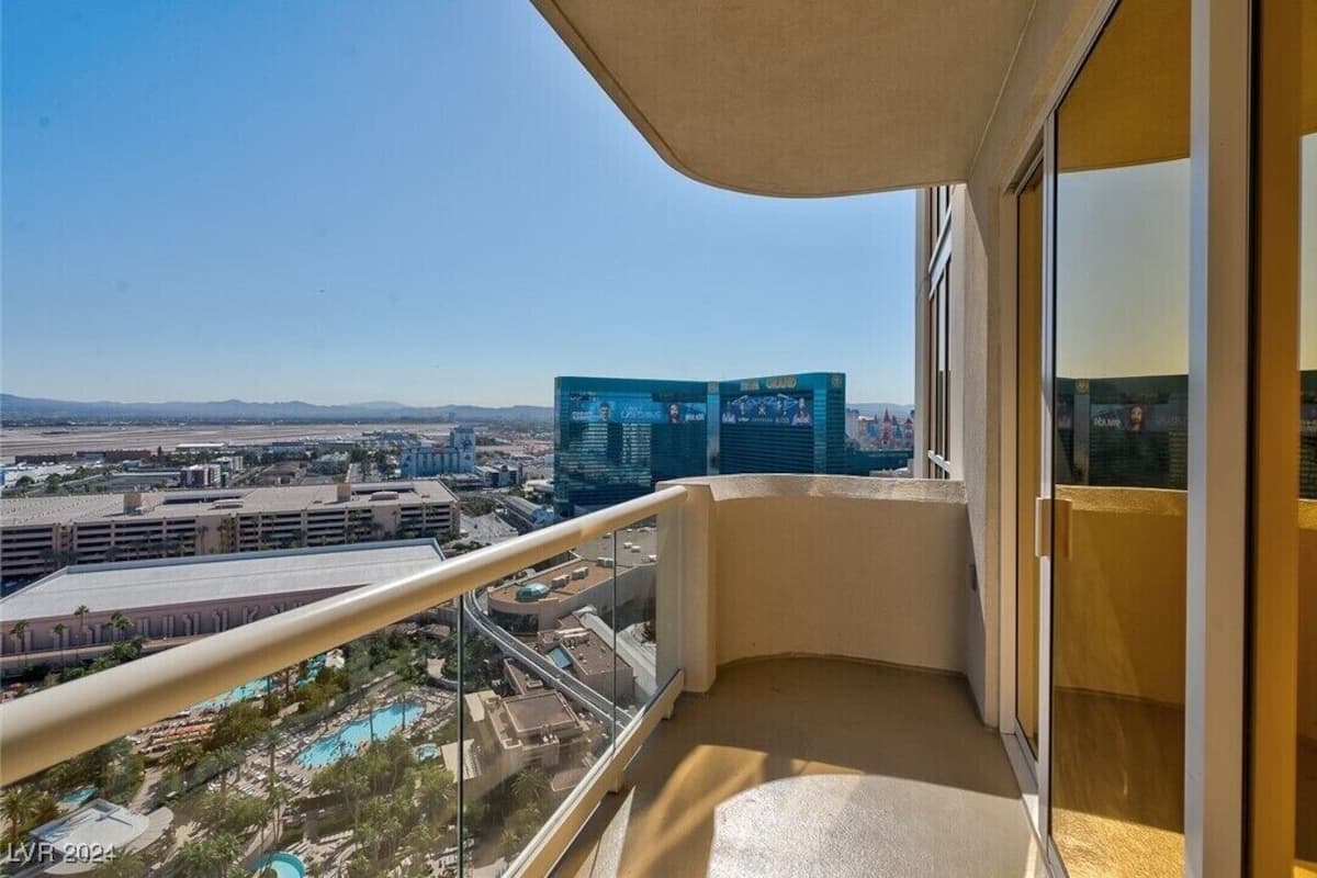 A balcony with a clear view of a cityscape, including buildings and a distant mountain range.