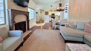A spacious living room with a fireplace, a television mounted on the wall, and a dining area with a chandelier. - Filbert Reserve (Paso Robles)