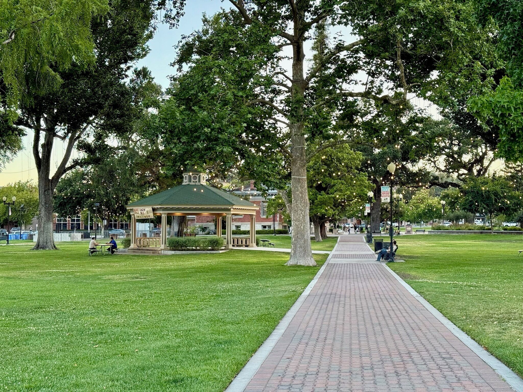A park with a gazebo, a paved walkway, and trees.