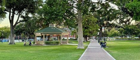 A park with a gazebo, a paved walkway, and trees.