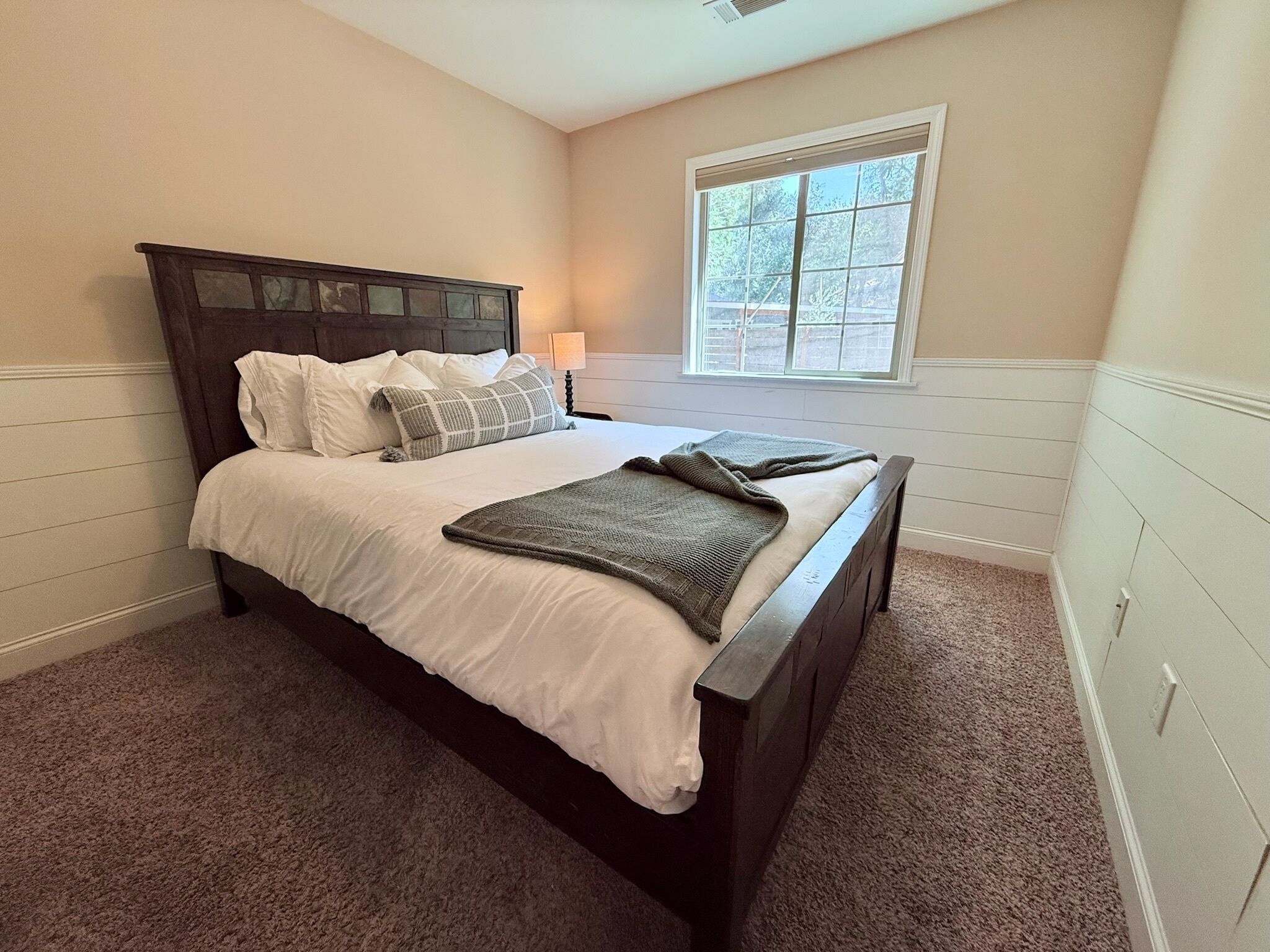 A bedroom with a bed, a window, and a nightstand.