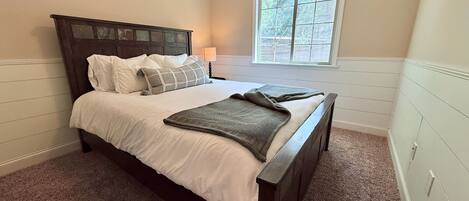 A bedroom with a bed, a window, and a nightstand.