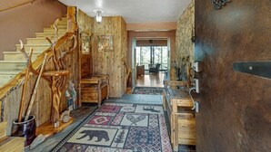 Eine hölzerne Treppe mit rustikalem Design führt zu einem Raum mit einem gemusterten Teppich und einer großen Metalldür.'