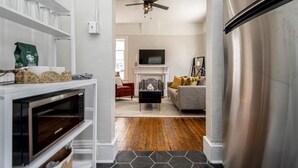 Una cocina moderna con microondas integrado, piso de madera y ventilador de techo.