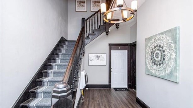 Una escalera con barandilla de madera y un suelo con estampado blanco y negro.