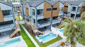 A modern multi-story residential building with a pool, outdoor seating, and a staircase connecting the levels. - Paradise on Bay Blvd – Heated Pool, Balconies, Elevator & 2 Blocks to Indian Rocks Beach (Indian Rocks Beach)