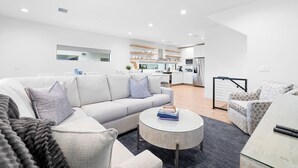 A modern living room with a grey sofa, a round coffee table, and a patterned armchair. - Paradise on Bay Blvd – Heated Pool, Balconies, Elevator & 2 Blocks to Indian Rocks Beach (Indian Rocks Beach)