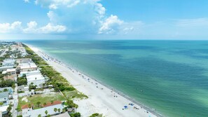 An aerial view of a coastal area with a long beach, clear blue water, and a row of buildings along the shore. - Paradise on Bay Blvd – Heated Pool, Balconies, Elevator & 2 Blocks to Indian Rocks Beach (Indian Rocks Beach)