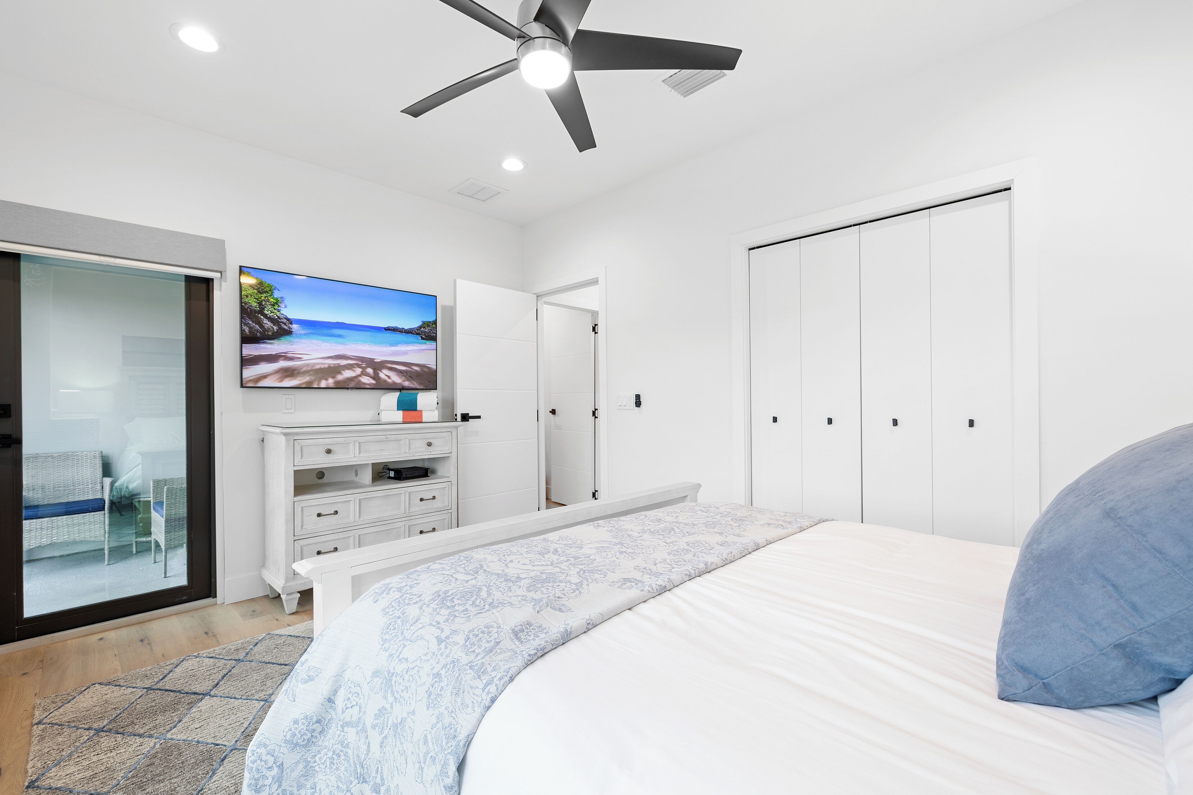 Ein Schlafzimmer mit Bett, Deckenventilator, Fernseher auf einer Kommode und einem Kleiderschrank.