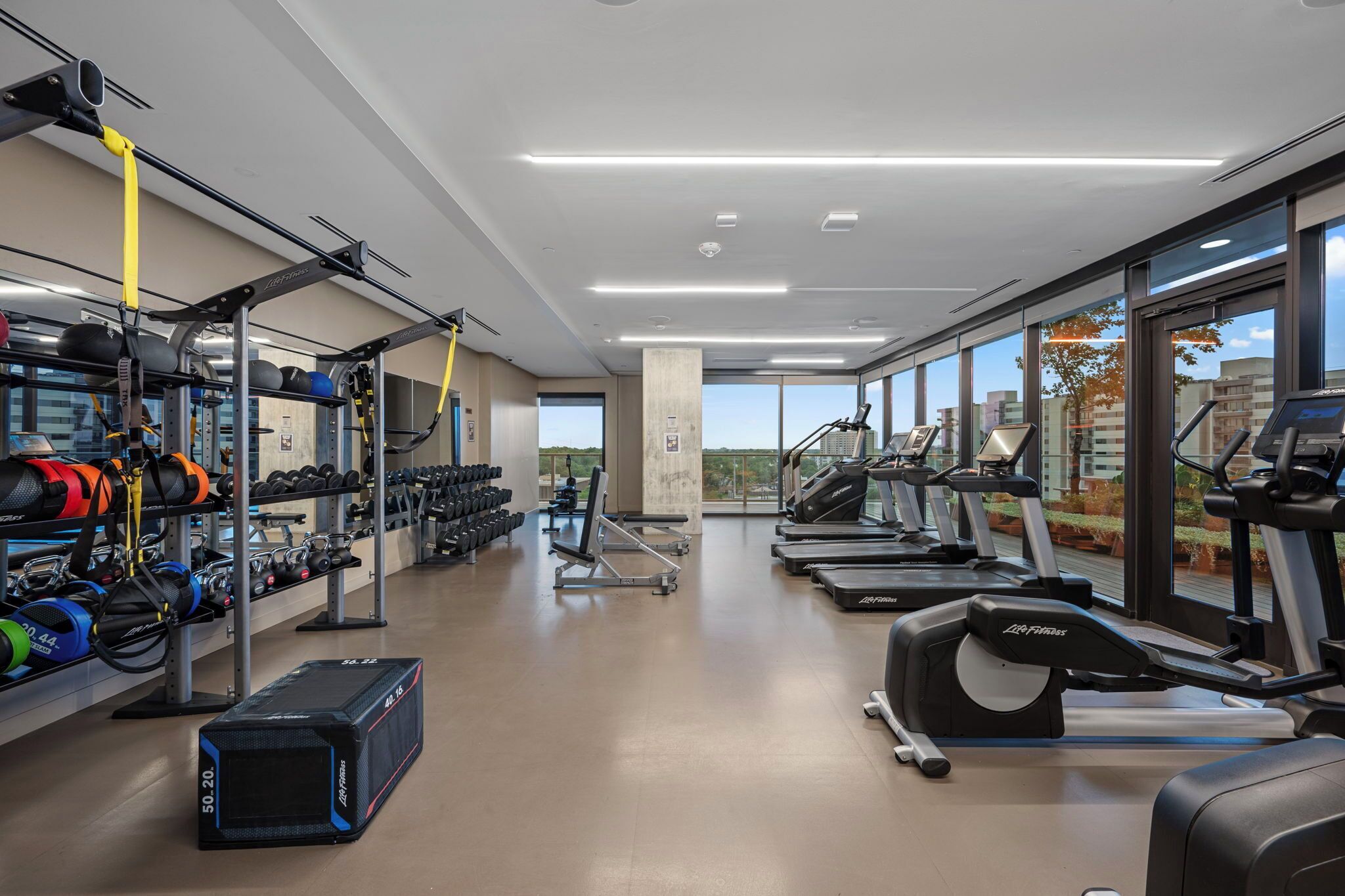 Et moderne fitnesscenter med løbebånd, styrkemaskiner samt forskellige vægte og elastikker.